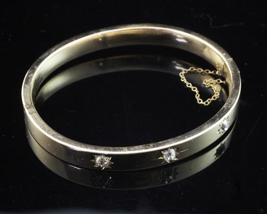 A gold and gypsy set three stone diamond hinged bangle, gross weight 12 grams.